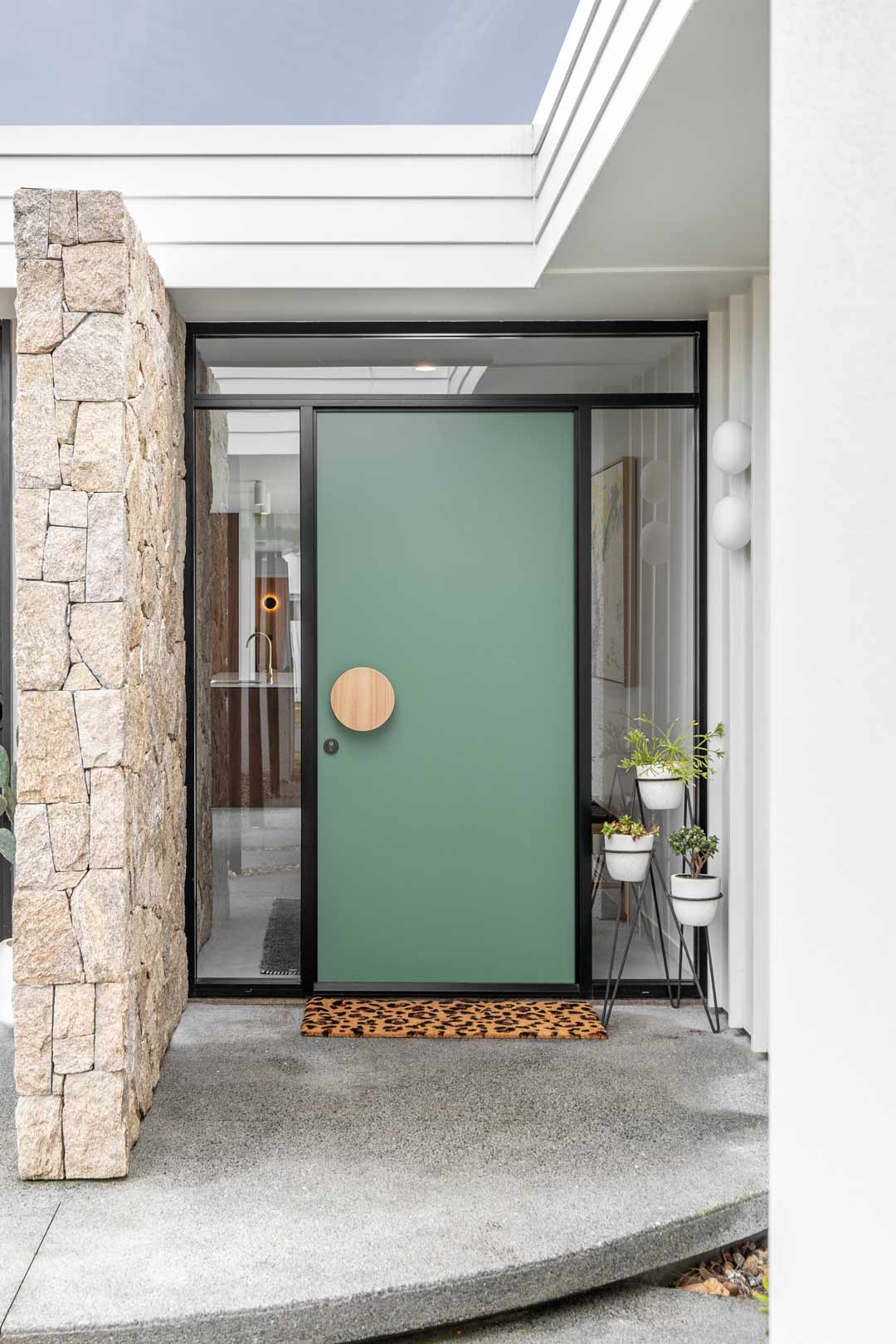 A bright green statement front door with a round timber door handle