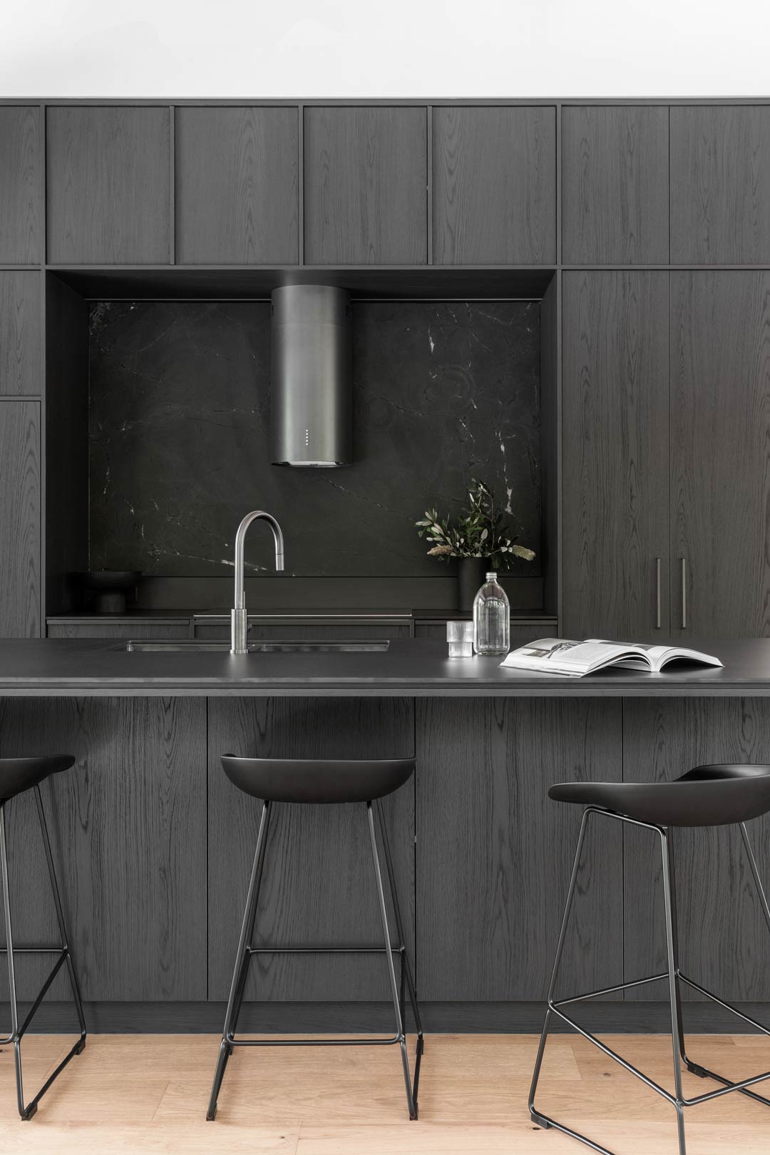 A dark monochromatic colour scheme kitchen with natural elements