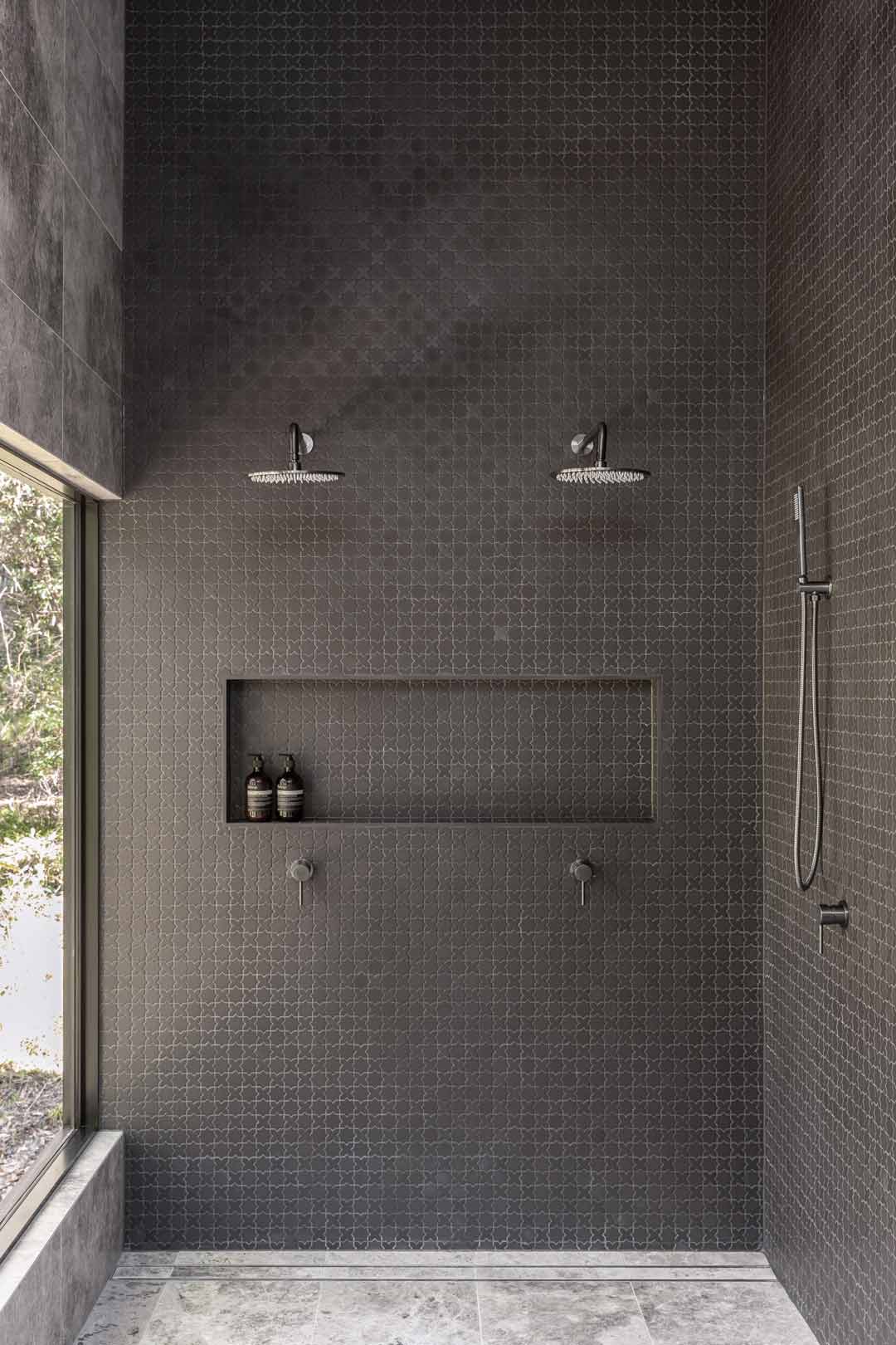 A double shower with brushed gunmetal tapware and a large window so you feel like you are showering in nature