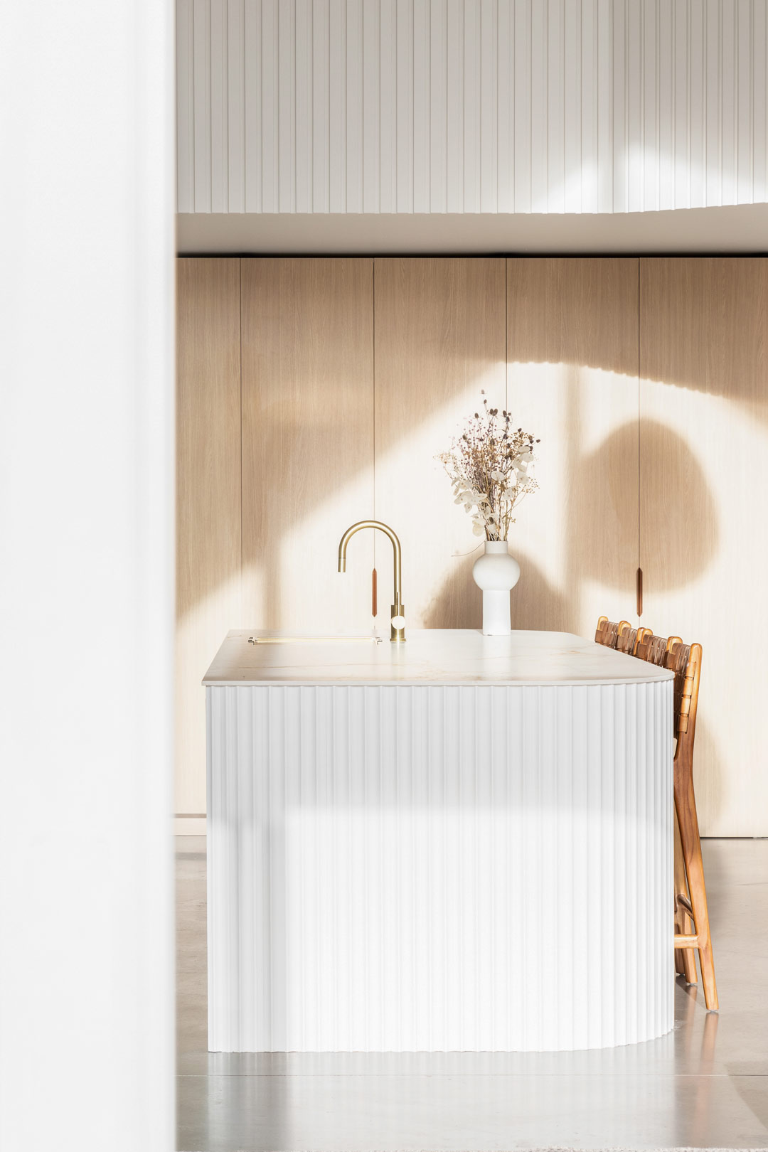 A kitchen brightened with gentle natural light creating interest and shapes through shadows