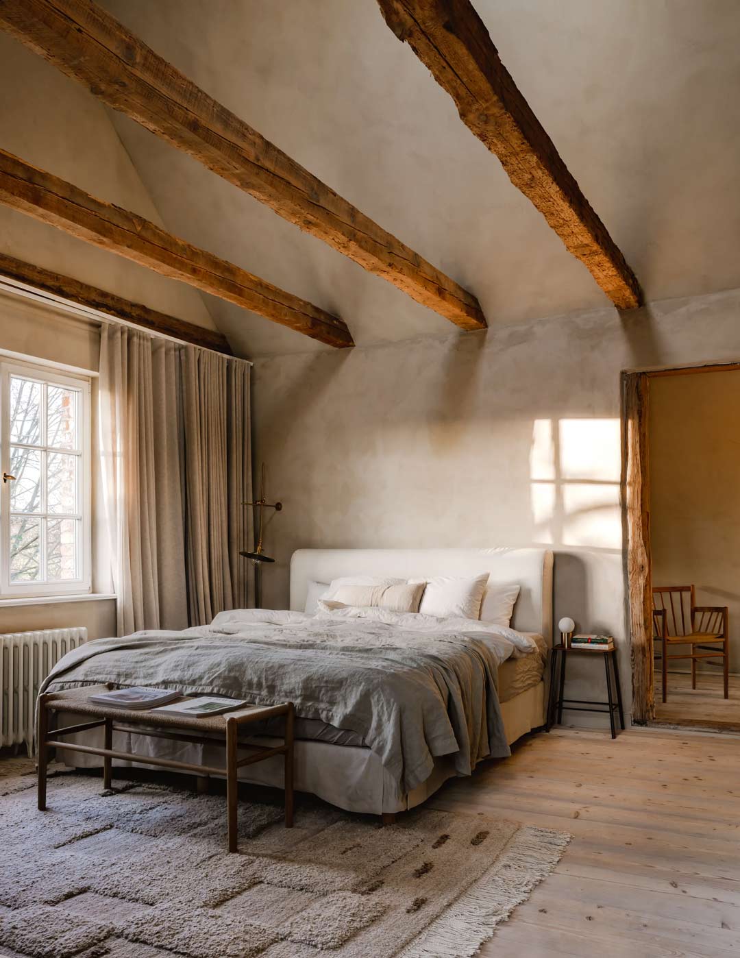 A muted natural colour palette bedroom with exposed timber beams for a wabi sabi design