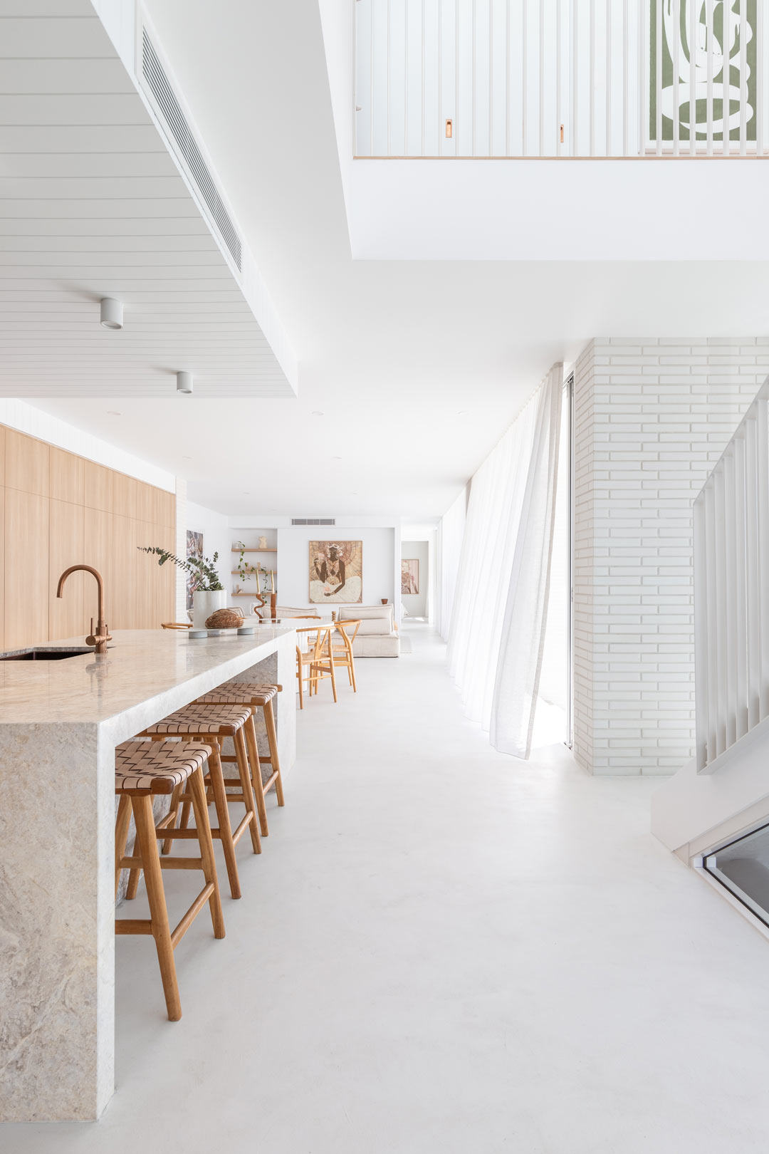 An open plan coastal home with a open void and large glass sliding doors with diffused natural light coming through sheer curtains