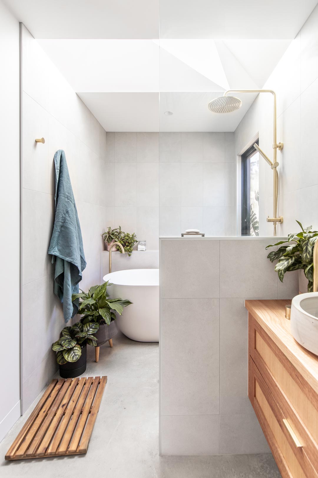 Indoor plants in a bathroom with brushed brass shower and a timber vanity