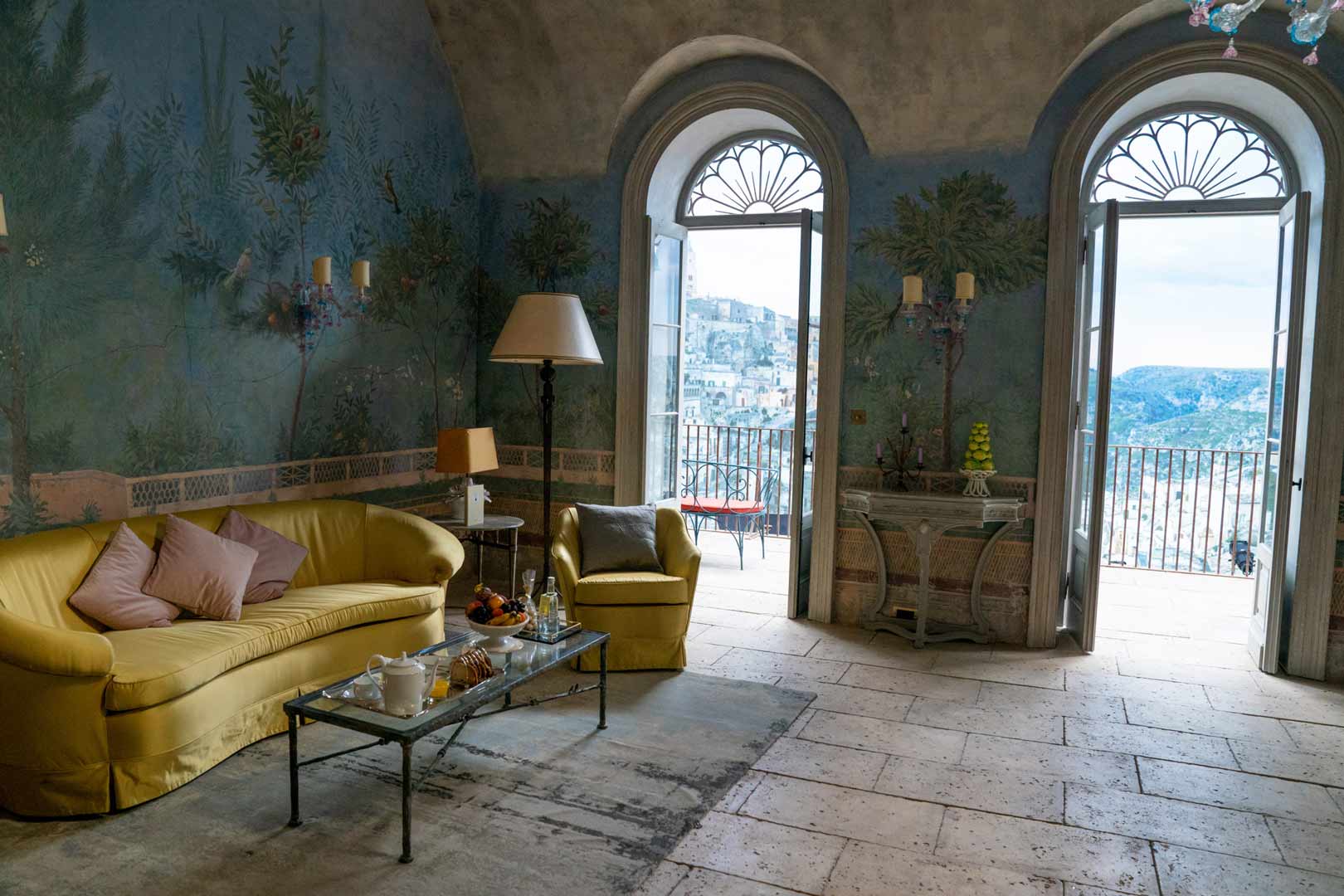 Interior Design In The Movies James Bond Italian Rustic Hilltop Hotel Suite With Blue Wall Mural Yellow Couch Arched Windows And Recessed Limestone Wall Niches 1 