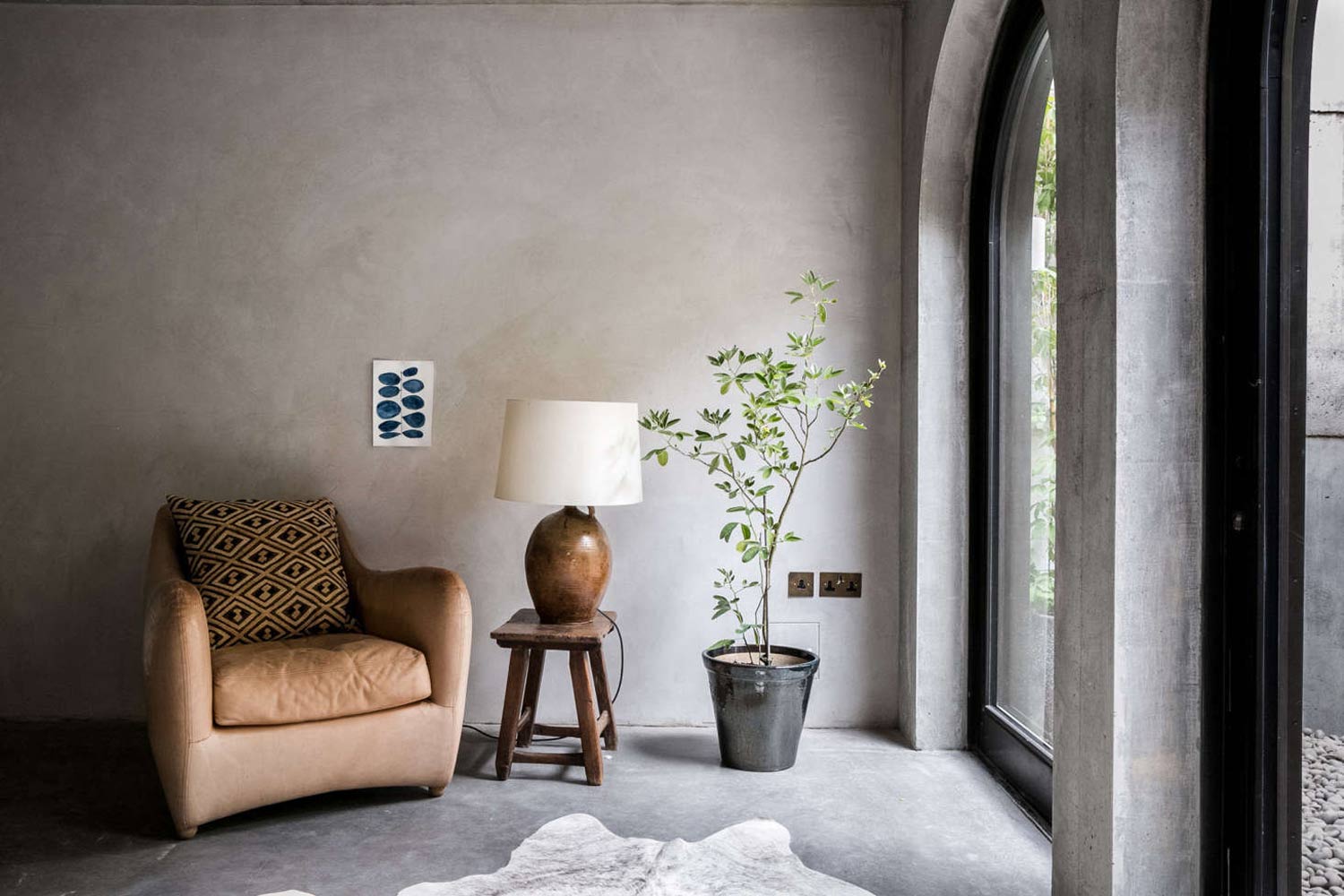 wabi sabi living room with a leather arm chair, textured walls and zen like plants indoors and out
